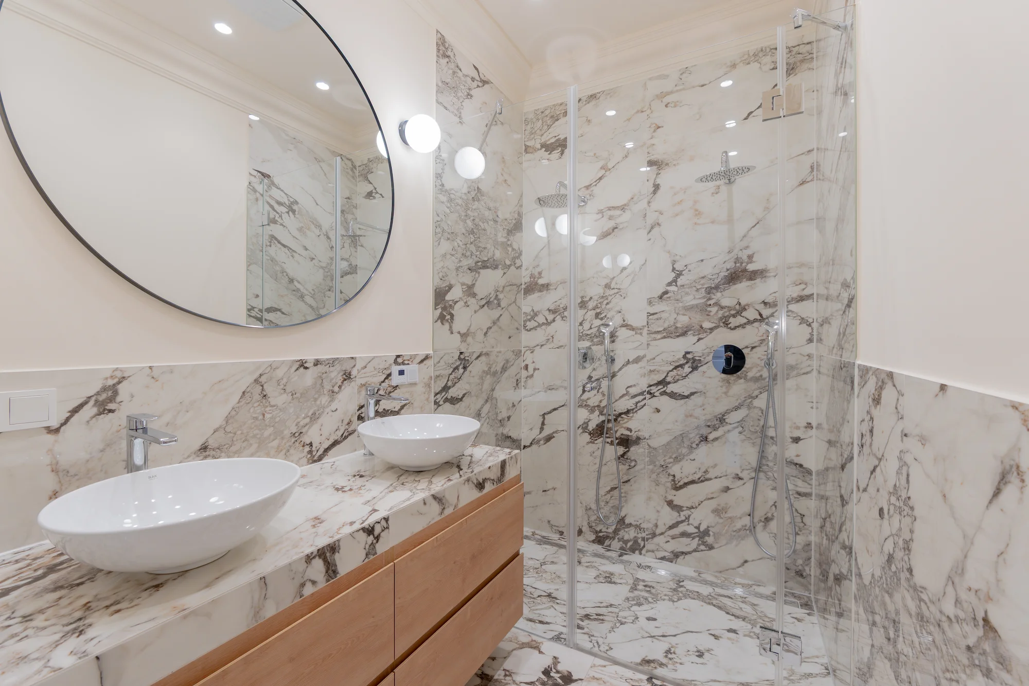 Badezimmer mit Dusche, Waschtisch und großformatigem Naturstein