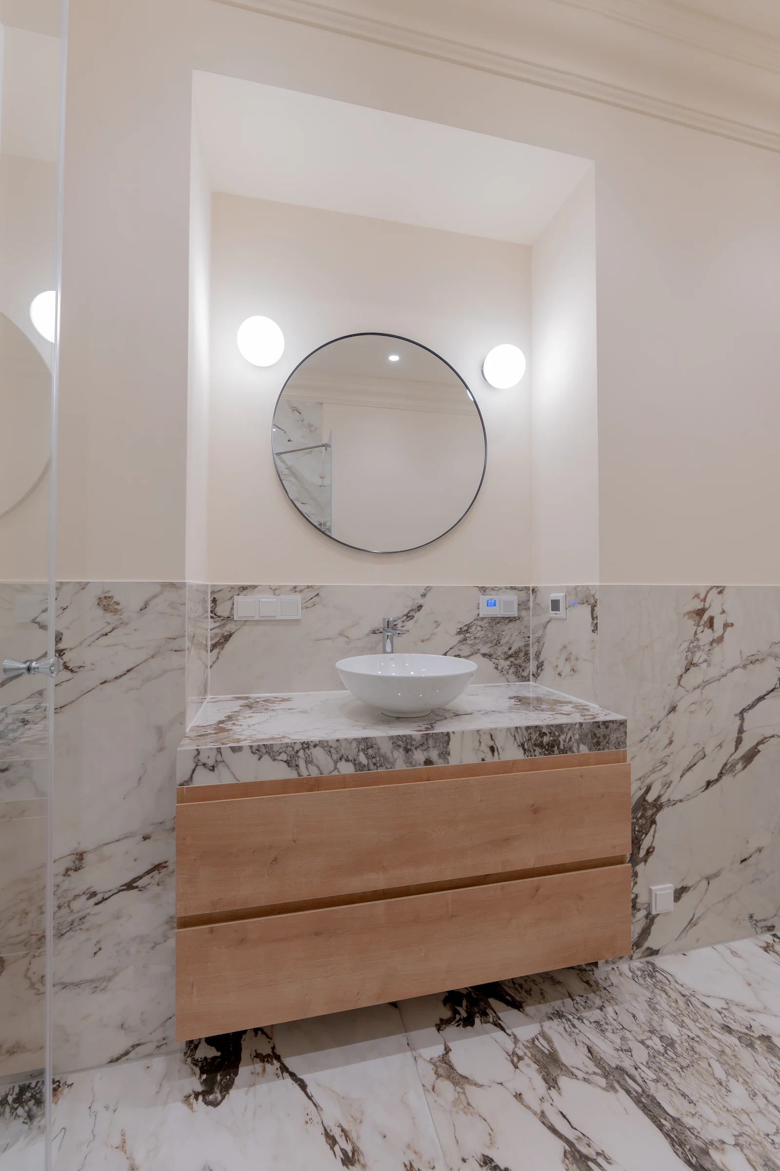 Waschtisch mit Rundspiegel und Naturstein im Badezimmer