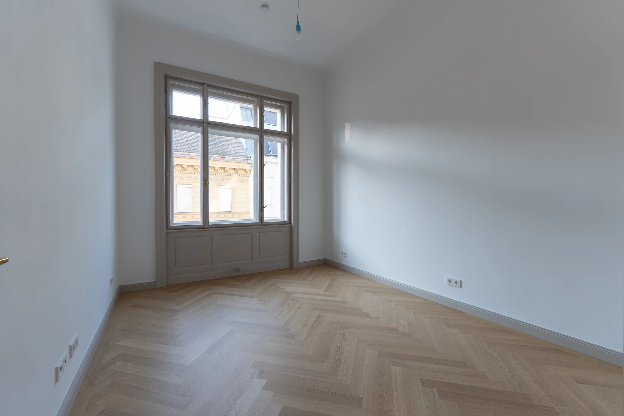 Helles Zimmer einer sanierten Wohnung in der Wohllebengasse mit Fischgrätparkett