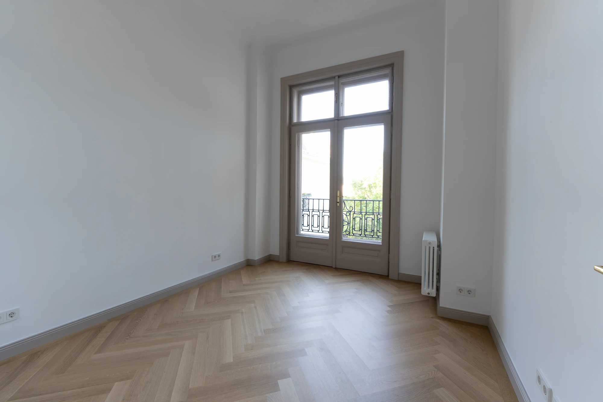 Weiteres Zimmer mit Fischgrätparkett und hoher Fensteröffnung