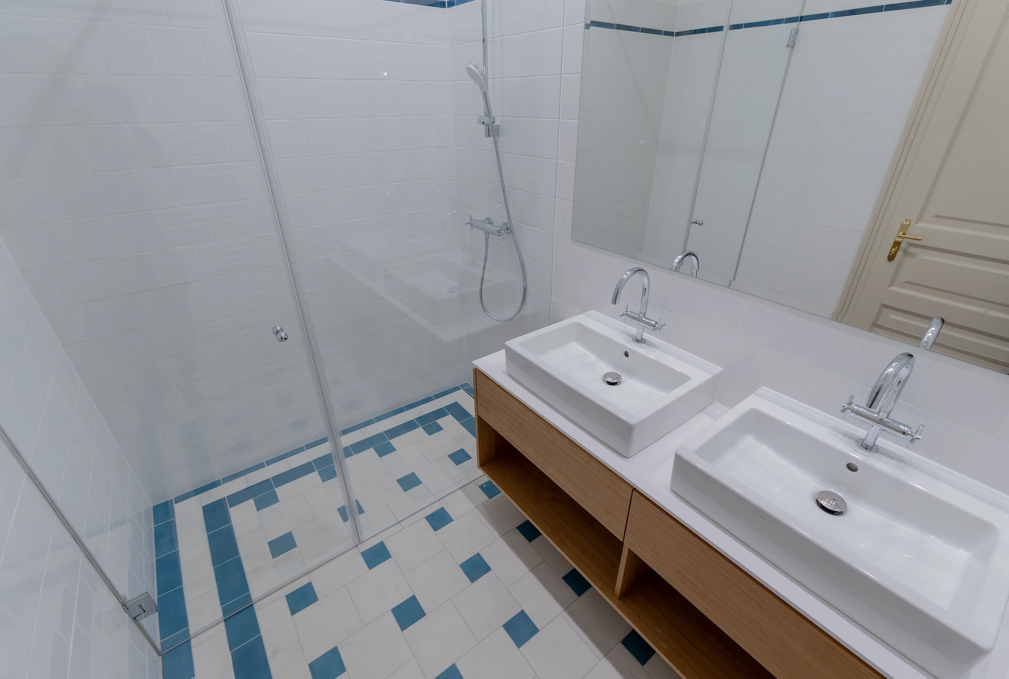 Badezimmer mit Doppelwaschtisch und blau akzentuiertem Fliesenboden