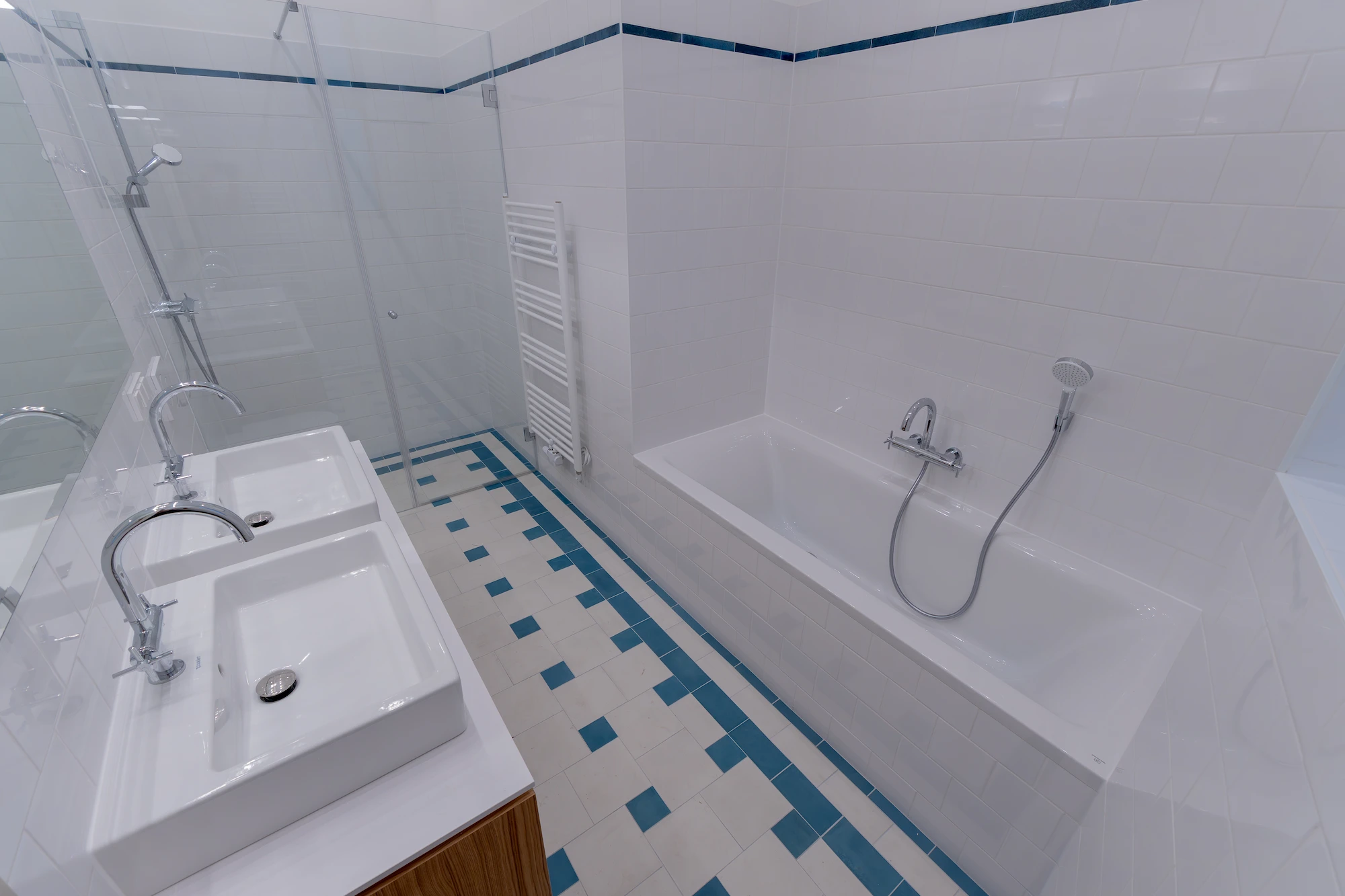 Badezimmer mit Badewanne und blau akzentuiertem Fliesenboden