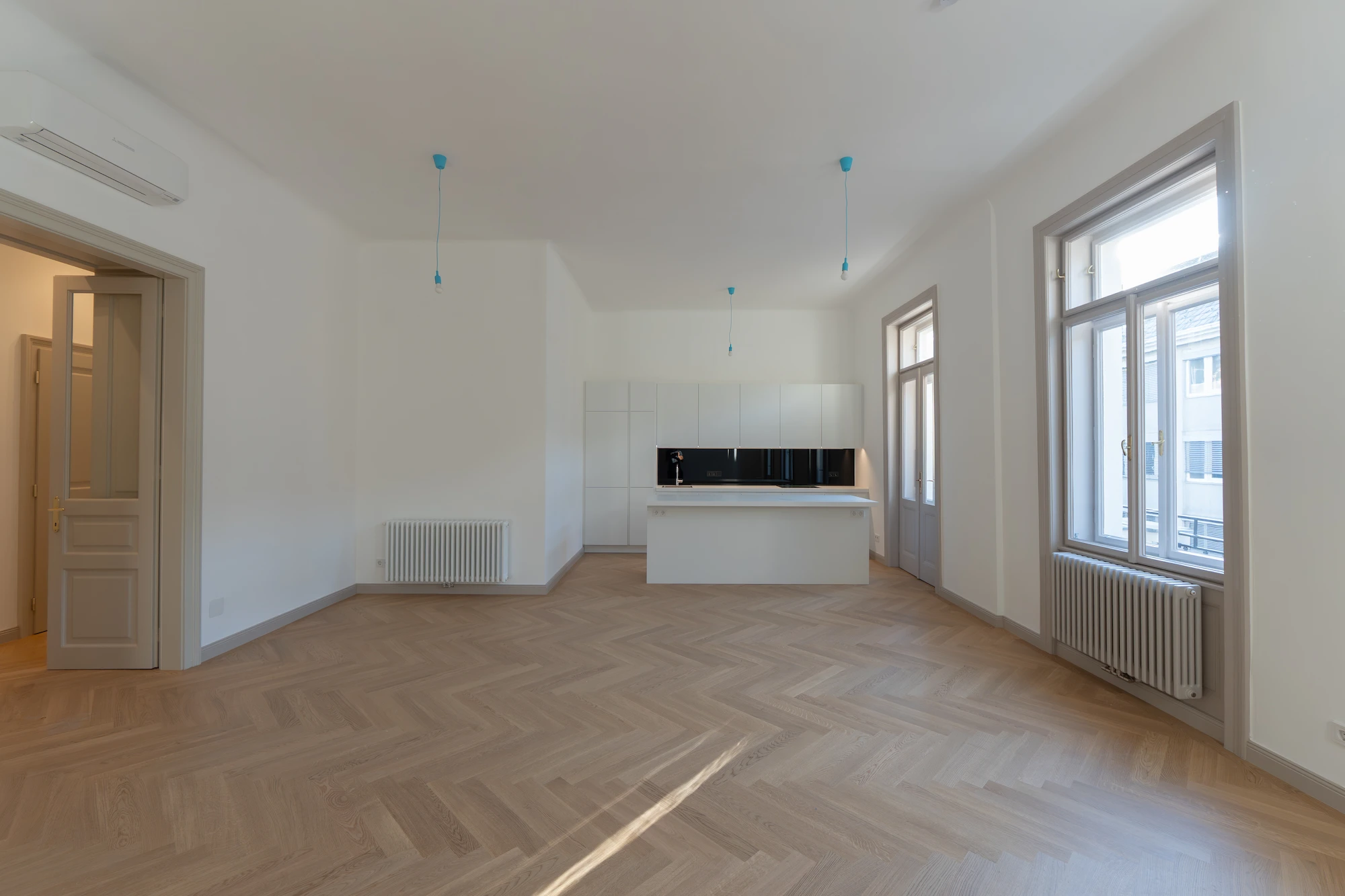 Großzügiger Wohnraum einer sanierten Altbauwohnung in der Wohllebengasse mit Fischgrätparkett und offener Küche