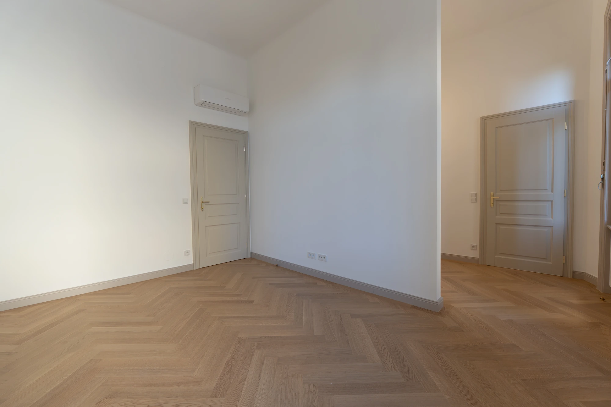 Helles Zimmer mit Fischgrätparkett in einer sanierten Altbauwohnung in Wien