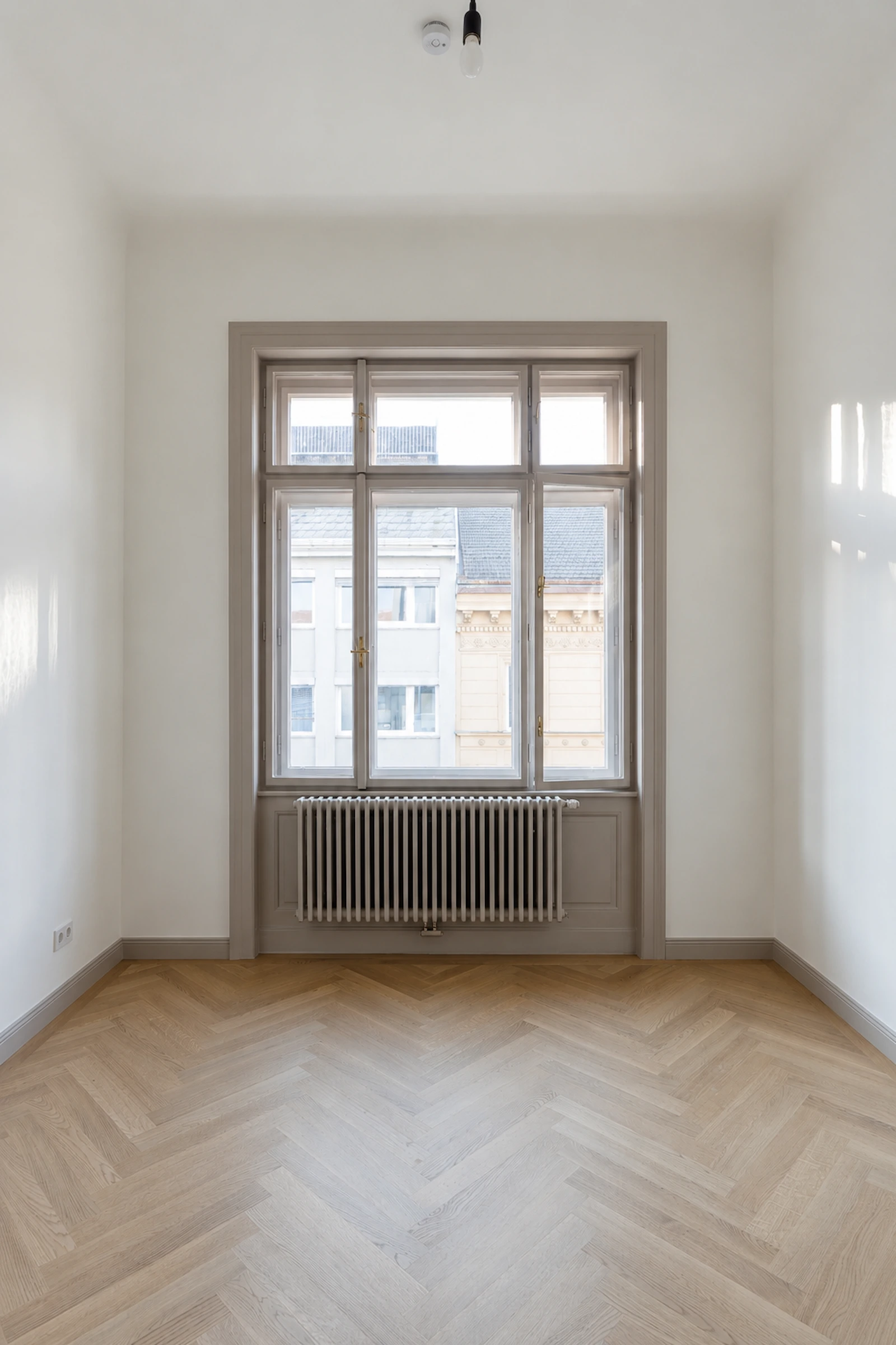 Helles Altbauzimmer mit Fischgrätparkett und klassischem Fenster